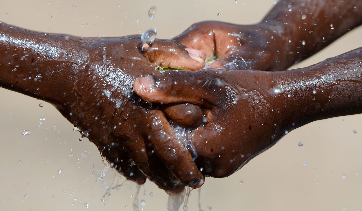 Hands being washed under flowing water, representing public health and WASH programmes